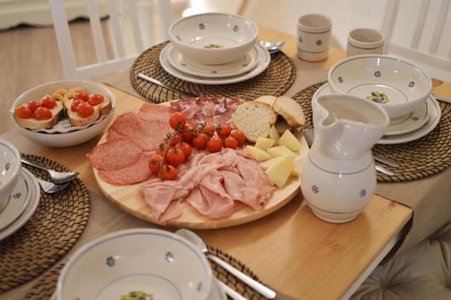 Tavola apparecchiata con salumi, formaggi e pomodorini