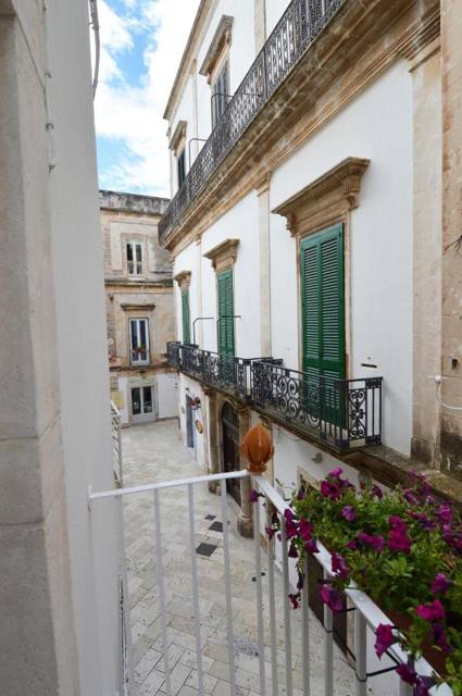 Balcone fiorito con persiane verdi sul centro storico