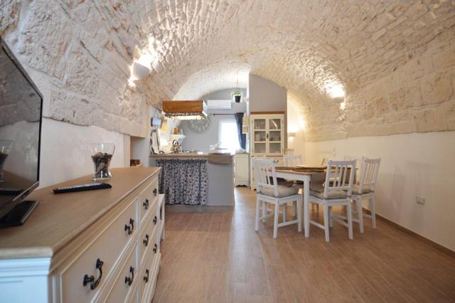 Zona giorno con soffitto a volta in pietra e cucina sullo sfondo